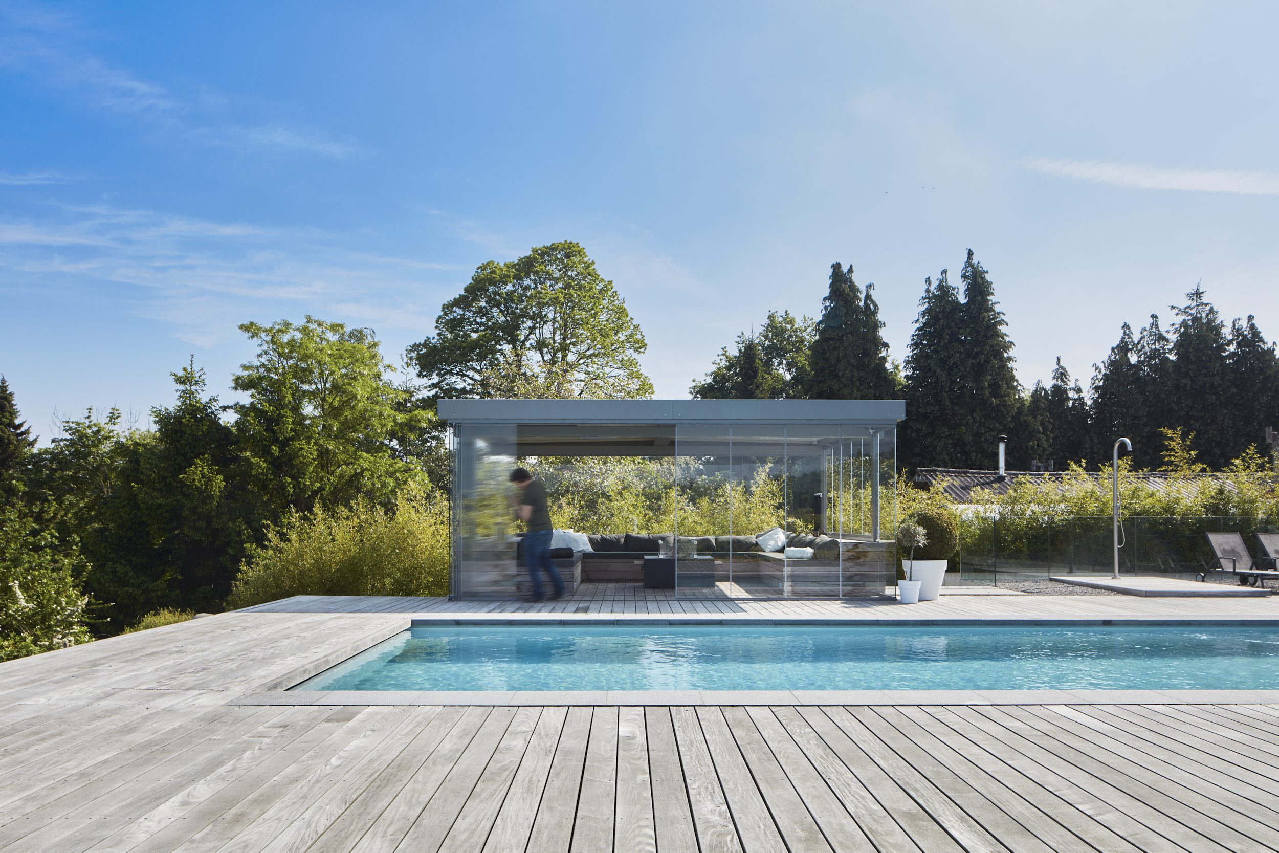 Man opent Sliding Glass ONE glazen schuifsysteem van modern poolhouse