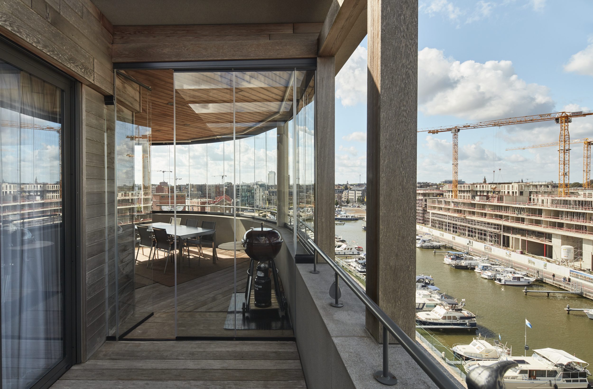 Transparante balkonbeglazing op hoog appartement met panoramisch zicht over jachthaven en stad voor optimaal comfort in alle seizoenen