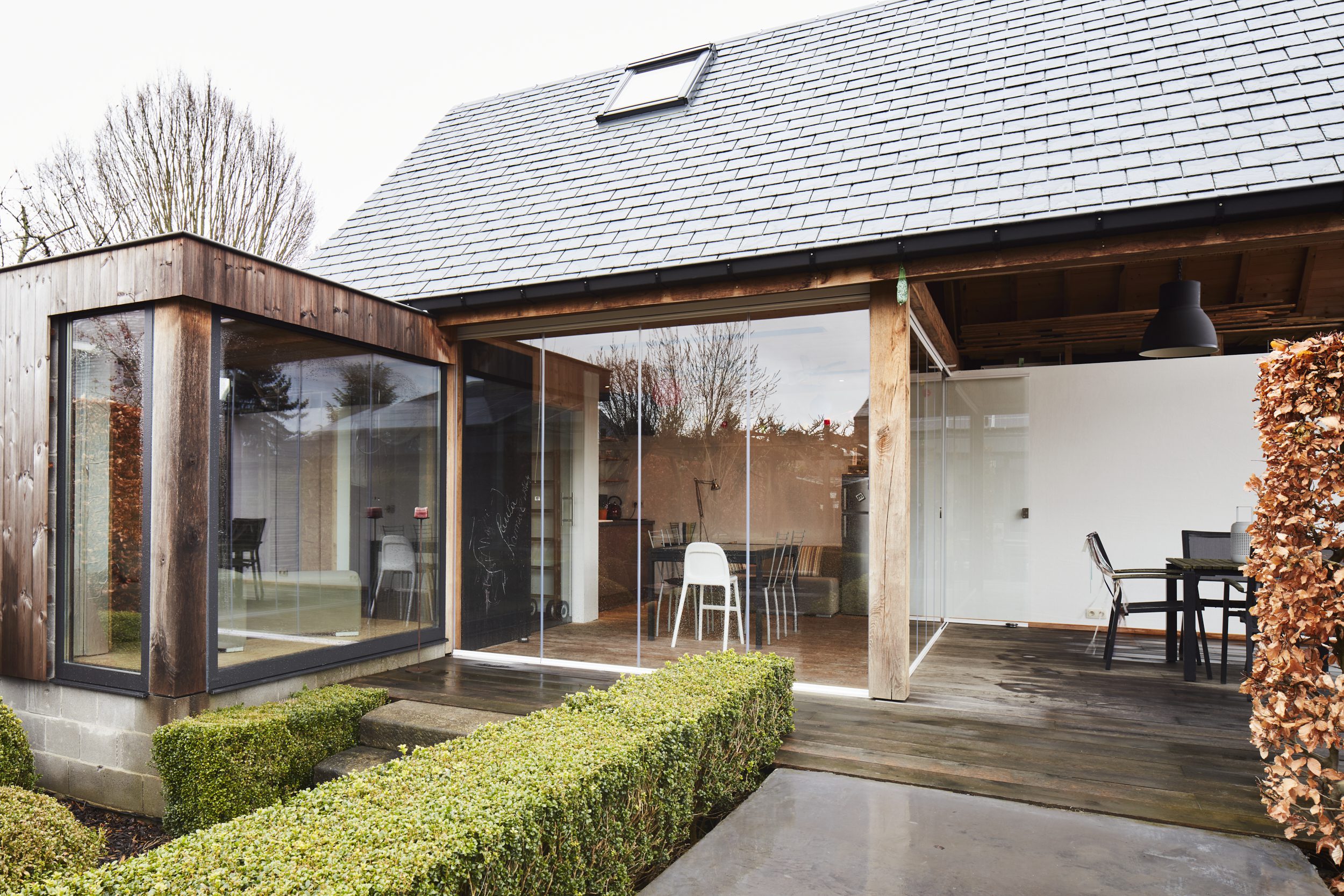 Veranda met glazen schuifwanden en overdekt terras aan woning met houten structuur