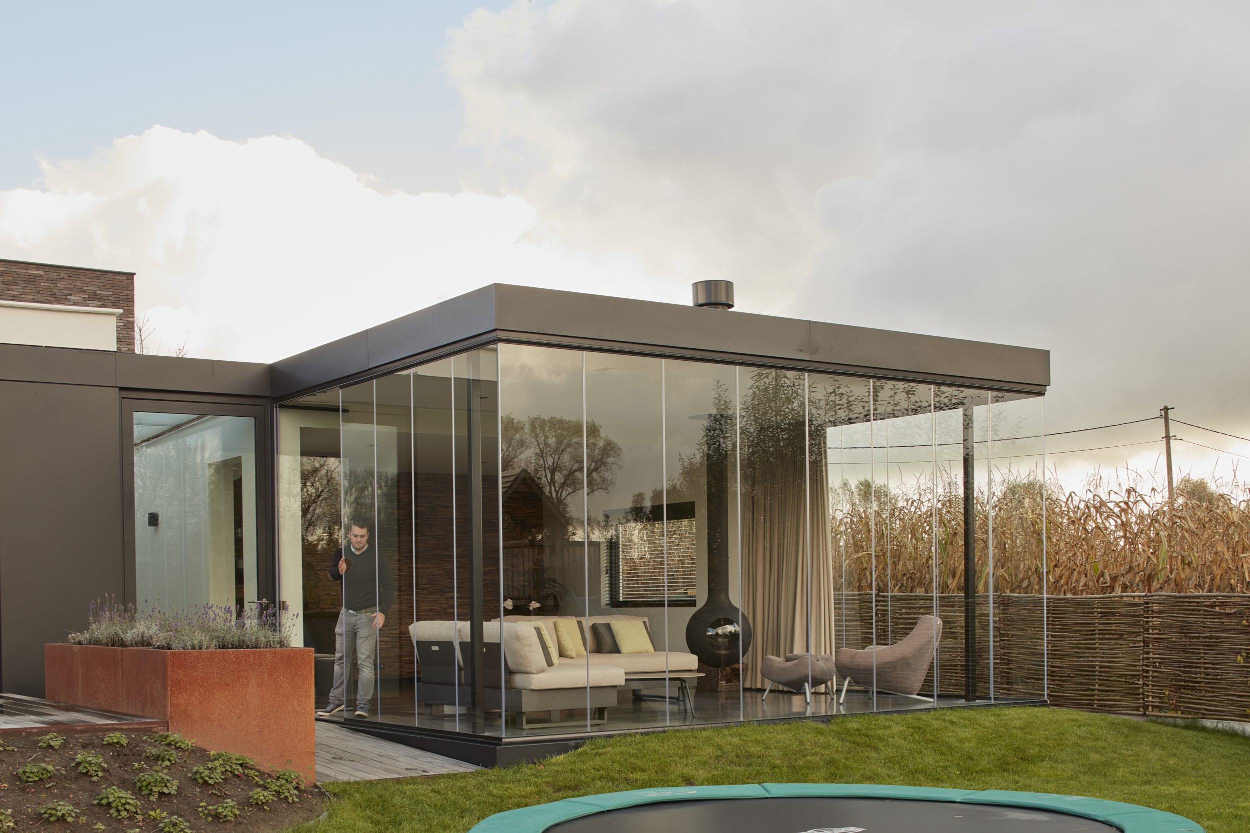 Moderne leefruimte met glazen schuifwanden en panoramische hoekbeglazing voor maximaal tuinzicht en lichtinval
