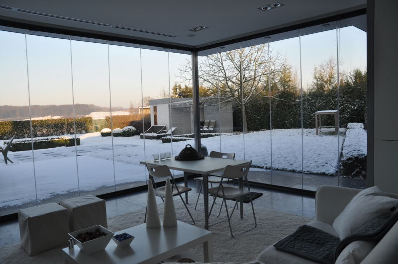 Glazen schuifwand rondom veranda met panoramisch tuinzicht en comfortabel gebruik tijdens winterse dagen