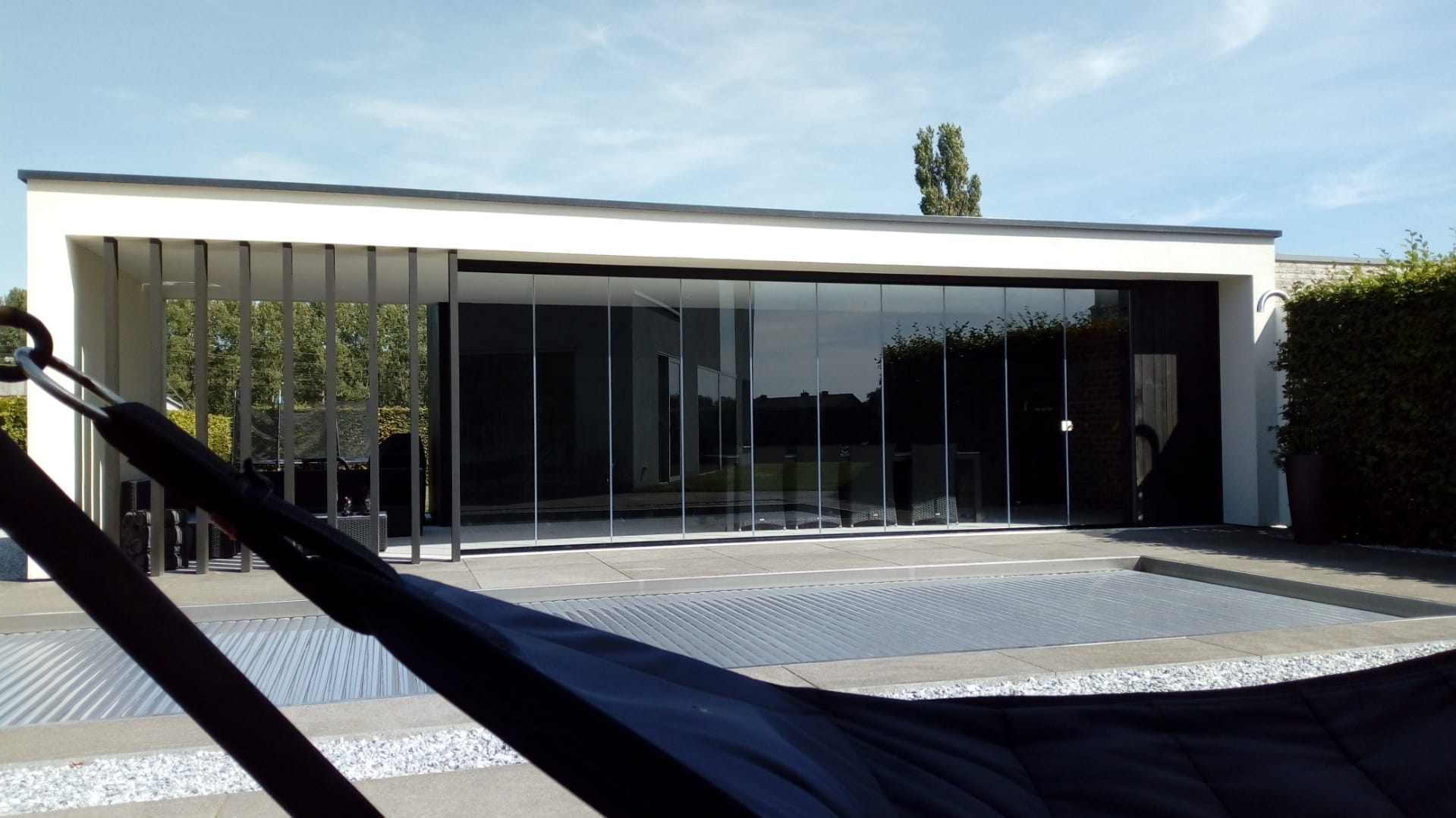 Moderne glazen schuifwand in poolhouse met zicht op zwembad