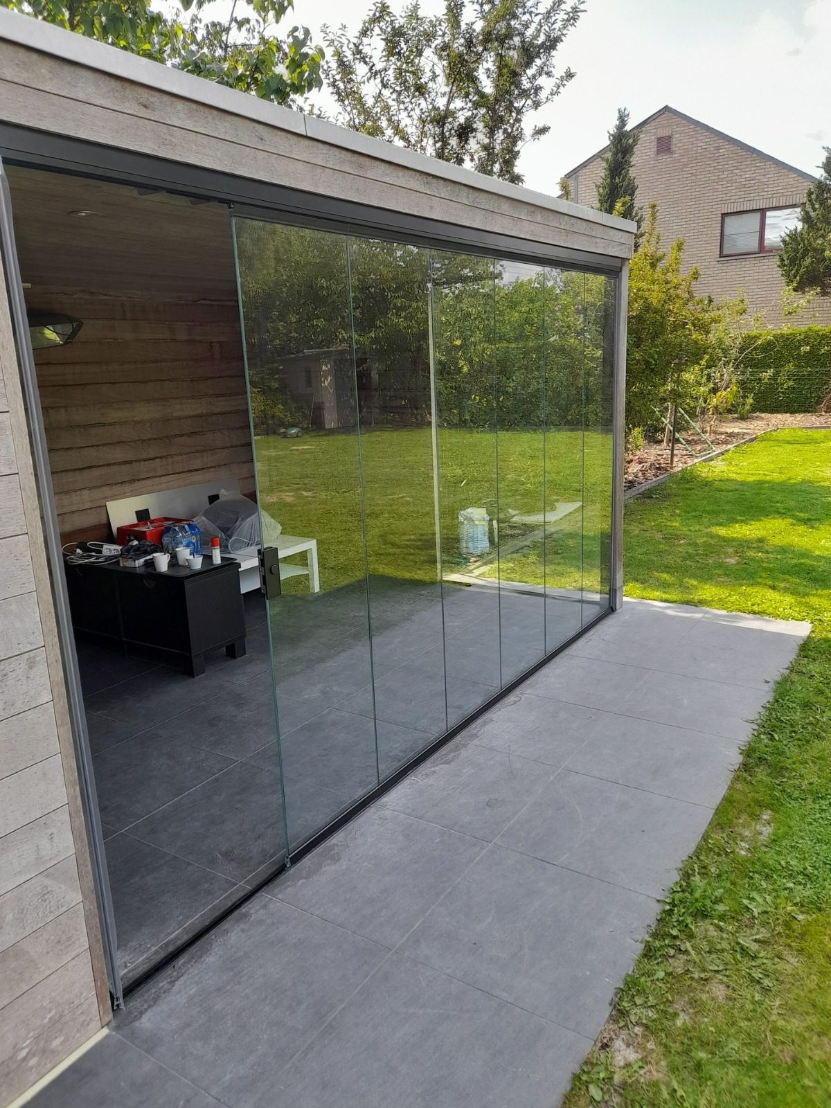 Glazen schuifpanelen aan modern poolhouse met slanke profielen en volledig zicht op tuin en buitenruimte