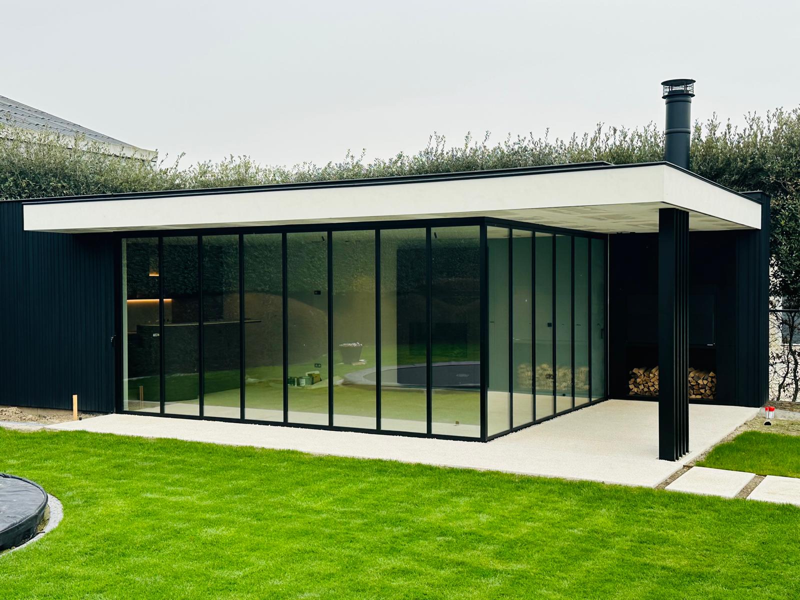 Modern poolhouse met zwarte aluminium schuifwanden en glazen hoekopstelling voor een strakke open tuinbeleving